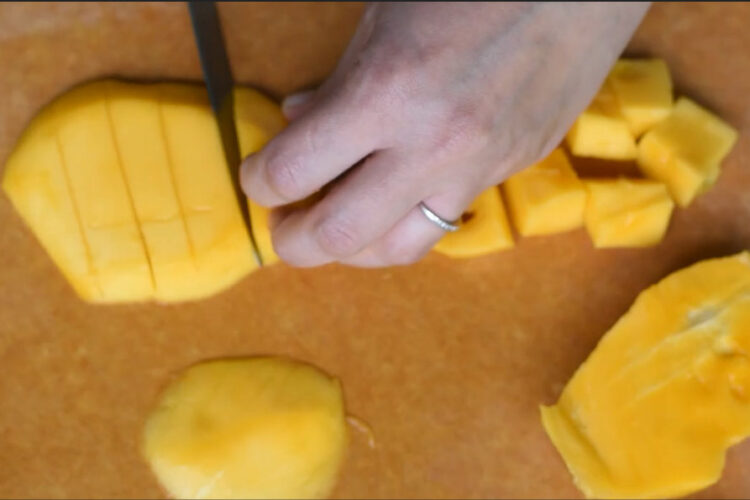 Peeled mango on cutting board by Plantainsandchallah.com